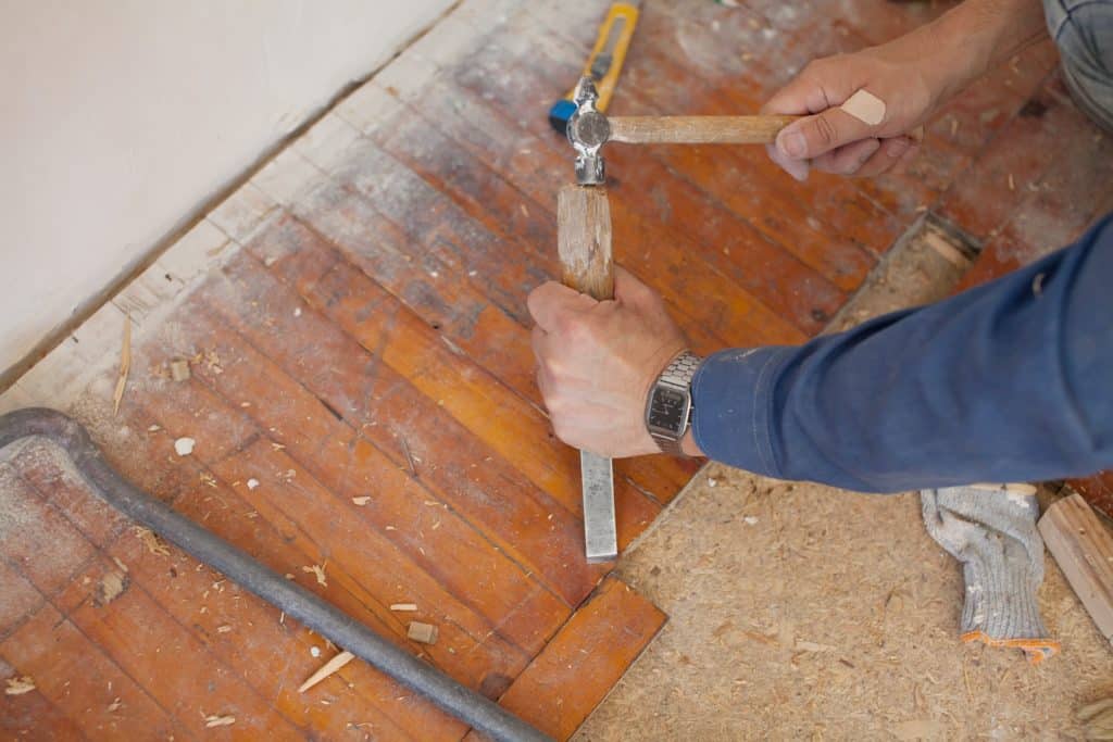 workman-removing-old-floor-close-up-view-his-gloved-hands